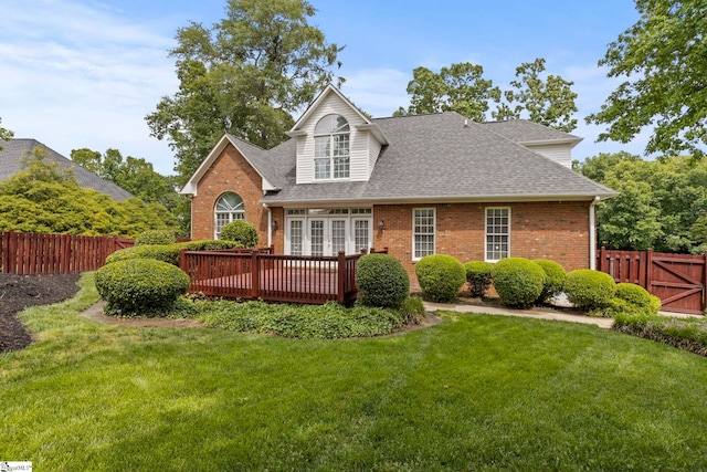 view of front of house with brick siding, fence, a front yard, and a deck