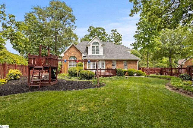 rear view of house featuring a yard, brick siding, a fenced backyard, and a deck