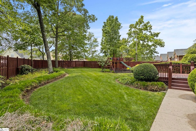 view of yard featuring a fenced backyard, a playground, and a wooden deck