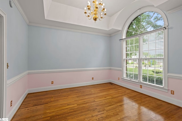 unfurnished room with plenty of natural light, wood finished floors, and a chandelier