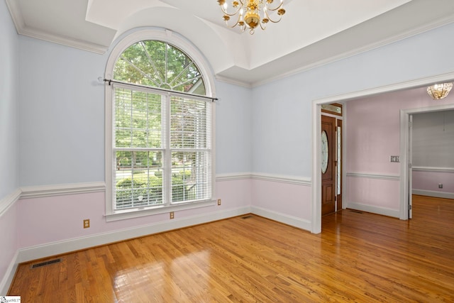 spare room featuring an inviting chandelier, baseboards, plenty of natural light, and light wood-type flooring