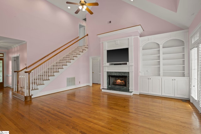 unfurnished living room featuring visible vents, a ceiling fan, a towering ceiling, and stairway