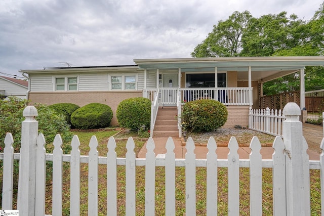 view of front of home with a fenced front yard, a porch, and brick siding