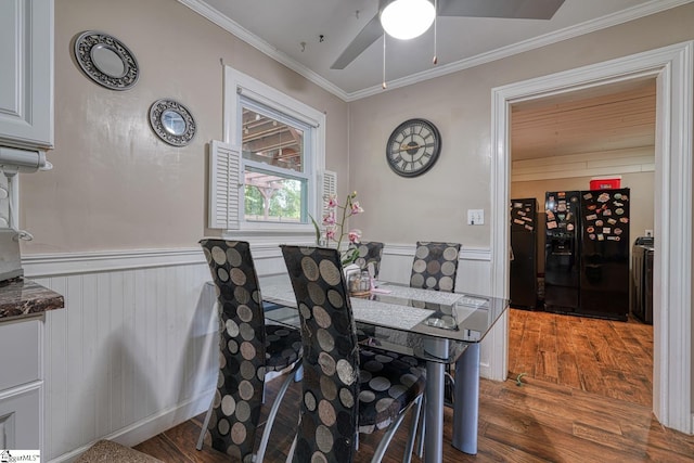 dining space with crown molding, a ceiling fan, wood finished floors, and a wainscoted wall