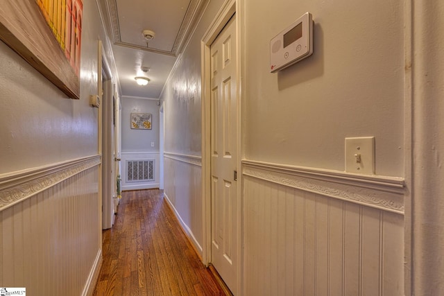 corridor featuring visible vents, a decorative wall, attic access, dark wood-style floors, and a wainscoted wall