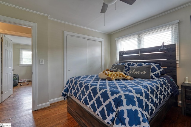 bedroom with a closet, ornamental molding, wood finished floors, baseboards, and a ceiling fan