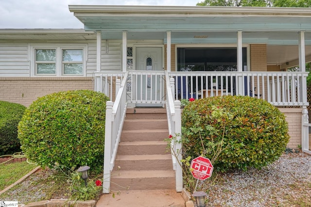 property entrance featuring a porch and brick siding