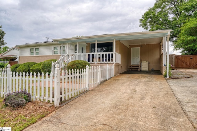 single story home with covered porch, fence private yard, brick siding, concrete driveway, and an attached carport