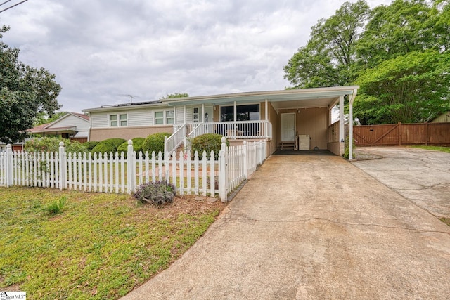 ranch-style house with covered porch, a fenced front yard, an attached carport, and driveway
