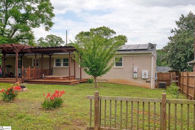 back of house featuring a lawn, roof mounted solar panels, central air condition unit, and fence