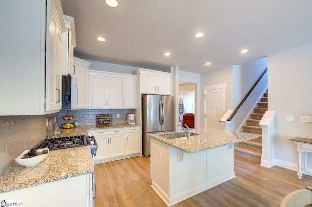 kitchen featuring light wood-style floors, freestanding refrigerator, white cabinetry, and tasteful backsplash