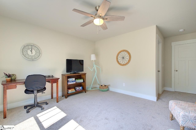 carpeted office space with a ceiling fan and baseboards