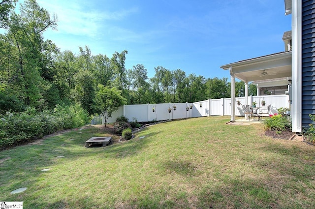 view of yard featuring ceiling fan, a fenced backyard, a patio area, and an outdoor fire pit
