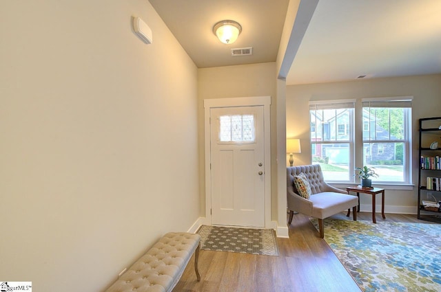 foyer featuring baseboards, wood finished floors, and visible vents