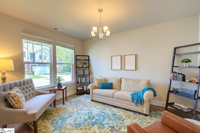 living room with baseboards, wood finished floors, and an inviting chandelier