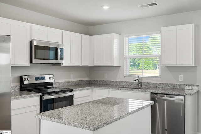 kitchen with stainless steel appliances, visible vents, white cabinetry, and a sink