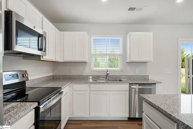 kitchen with visible vents, dark wood-type flooring, white cabinets, a sink, and appliances with stainless steel finishes