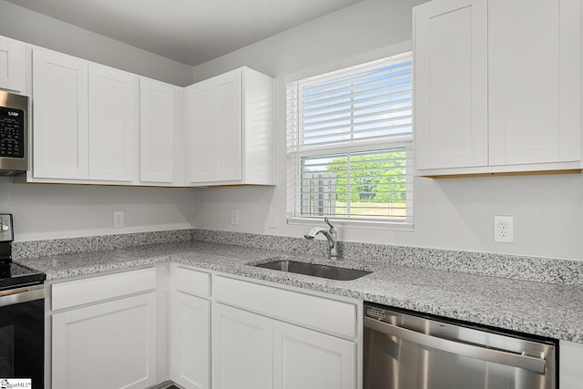 kitchen featuring white cabinets, light stone countertops, appliances with stainless steel finishes, and a sink