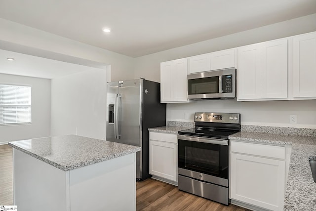 kitchen featuring white cabinets, appliances with stainless steel finishes, light stone counters, recessed lighting, and wood finished floors