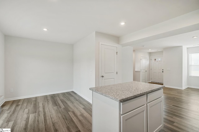 interior space featuring a center island, recessed lighting, baseboards, and wood finished floors