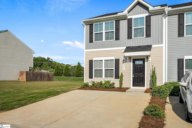 view of property featuring fence, board and batten siding, a patio area, and a front lawn