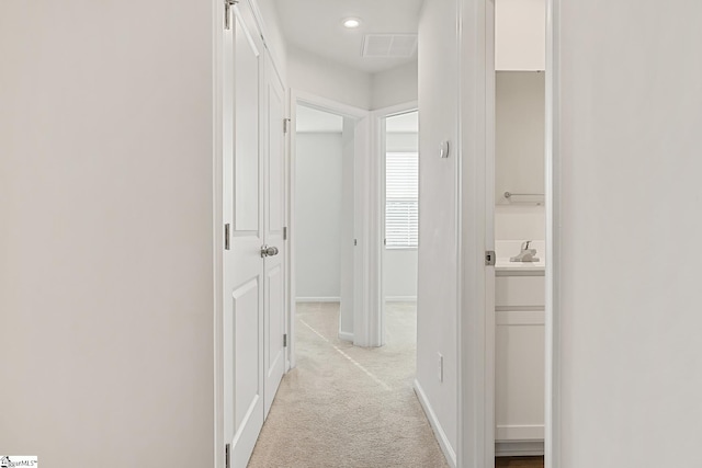 hall with a sink, baseboards, recessed lighting, and light colored carpet