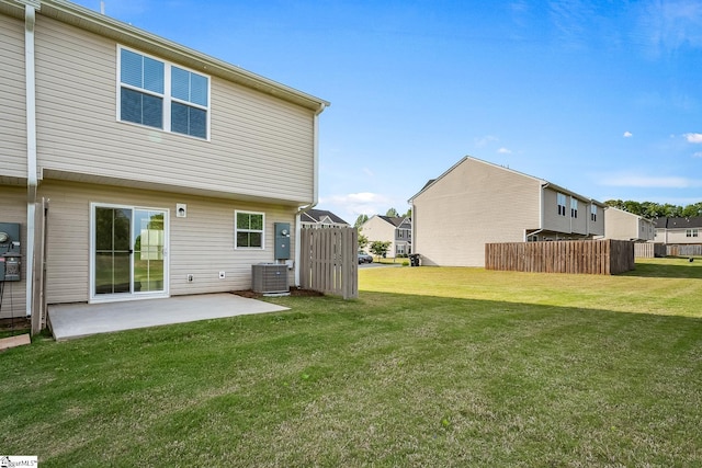 back of property with a lawn, fence, central AC unit, and a patio area