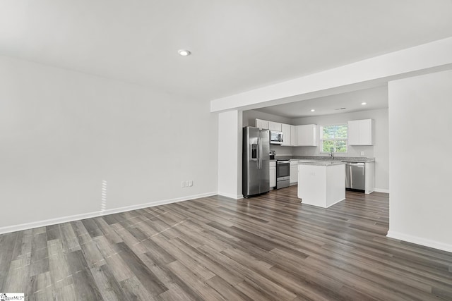 unfurnished living room featuring recessed lighting, a sink, baseboards, and dark wood-style floors