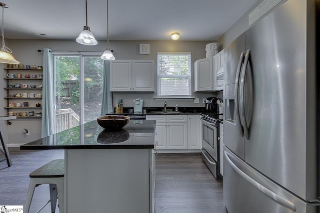 kitchen featuring plenty of natural light, a kitchen island, stainless steel appliances, and white cabinetry