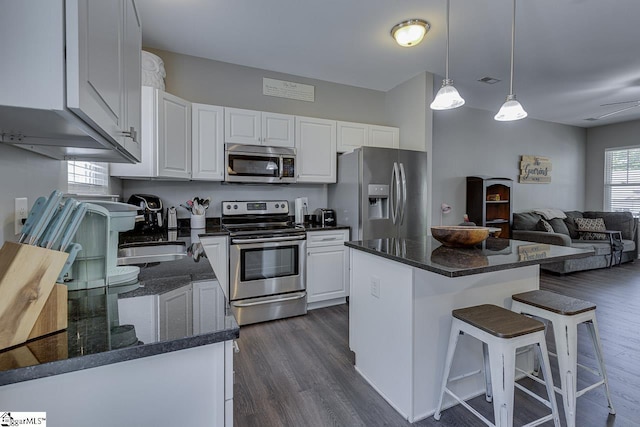 kitchen featuring white cabinetry, appliances with stainless steel finishes, dark wood finished floors, and a center island