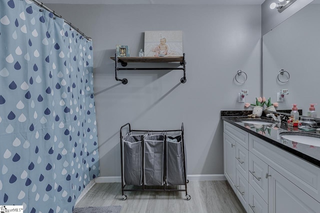bathroom with a sink, double vanity, wood finished floors, and a shower with shower curtain