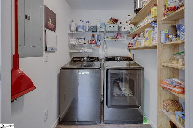laundry room featuring baseboards, laundry area, washer and clothes dryer, and electric panel