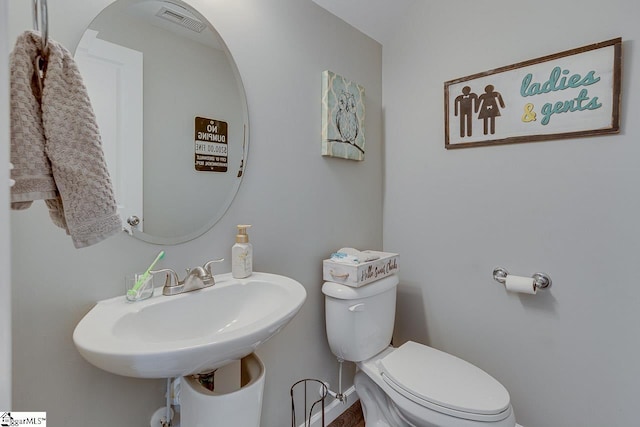half bathroom featuring a sink, baseboards, and toilet