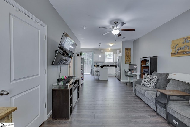living area with dark wood-style flooring and a ceiling fan