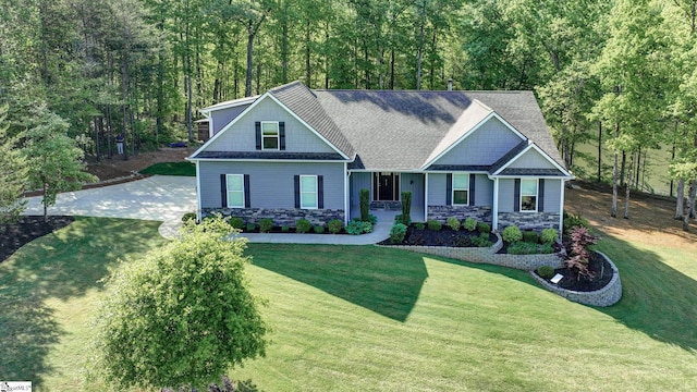 view of front facade with a view of trees, a front lawn, and stone siding