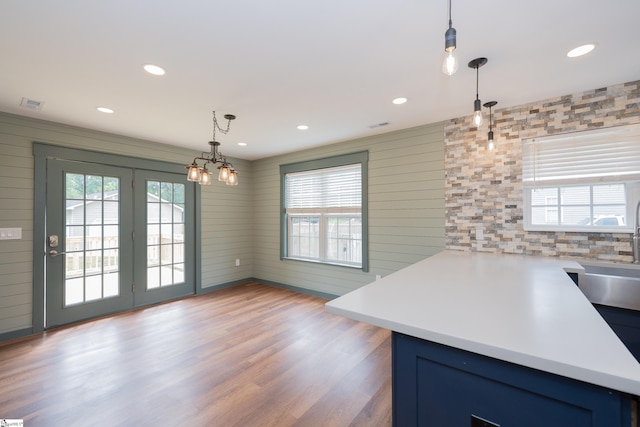 kitchen featuring a healthy amount of sunlight, blue cabinets, wood finished floors, and decorative light fixtures