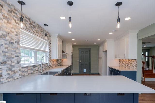 kitchen featuring light countertops, decorative backsplash, a peninsula, and white cabinets