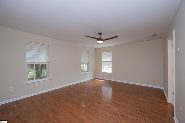 empty room featuring a ceiling fan, baseboards, visible vents, and wood finished floors