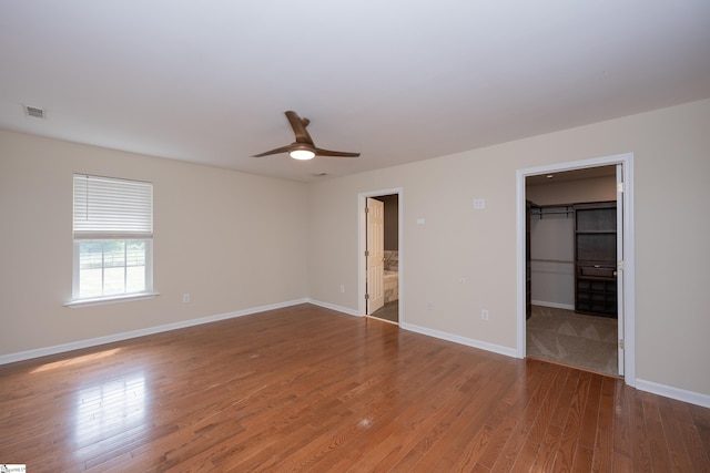 unfurnished bedroom with baseboards, wood finished floors, and a spacious closet