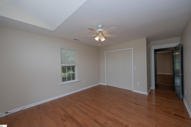 unfurnished bedroom with ceiling fan, visible vents, wood finished floors, baseboards, and a closet