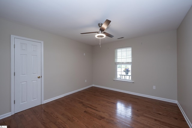 spare room featuring visible vents, a ceiling fan, dark wood-style flooring, and baseboards