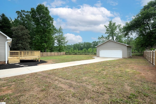 view of yard featuring fence, a detached garage, an outdoor structure, and a deck