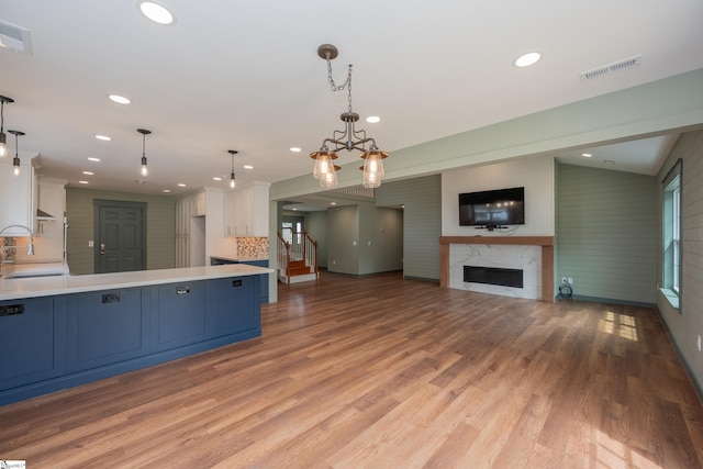 kitchen with decorative backsplash, a peninsula, light countertops, white cabinetry, and blue cabinetry