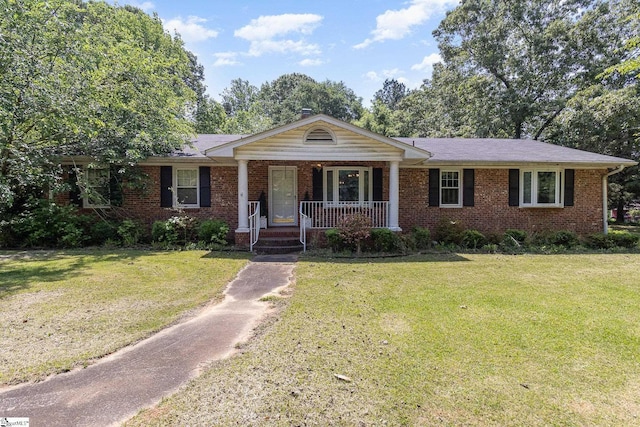 ranch-style house featuring covered porch, brick siding, and a front yard