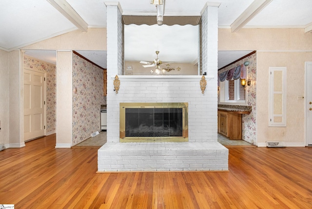 unfurnished living room featuring crown molding, a ceiling fan, wallpapered walls, vaulted ceiling with beams, and wood finished floors