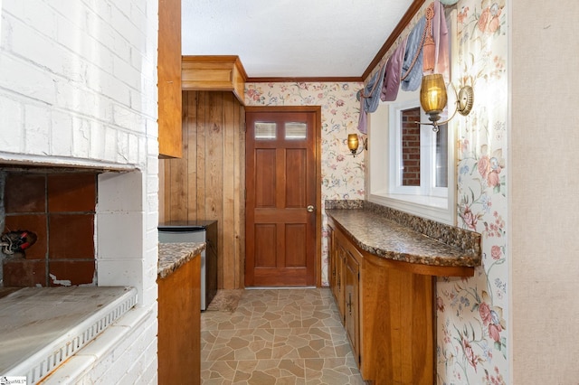 interior space featuring crown molding, stone finish floor, and wallpapered walls