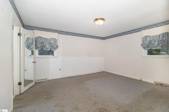 spare room featuring baseboards, visible vents, and carpet