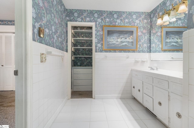 full bathroom featuring tile walls, vanity, a wainscoted wall, a closet, and wallpapered walls