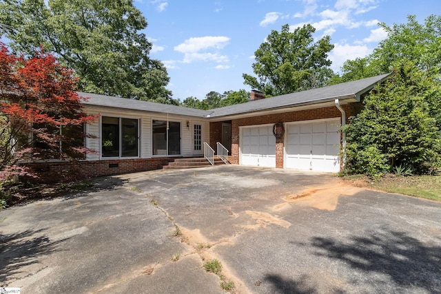 single story home featuring a garage, a chimney, concrete driveway, and brick siding