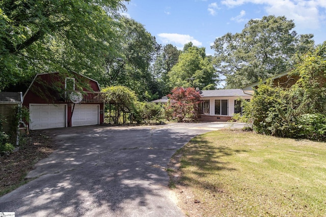 view of front facade featuring a garage, an outbuilding, concrete driveway, and a front lawn